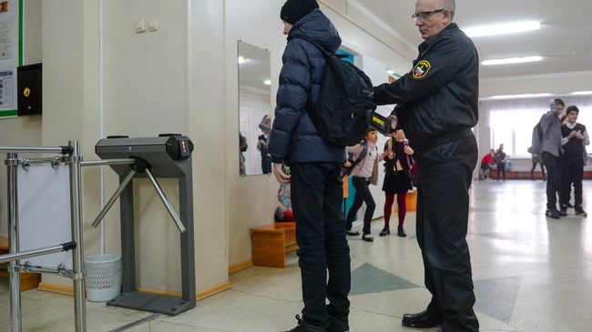 Сотрудник службы безопасности проверяет ученика в средней общеобразовательной школе Сотрудник службы безопасности проверяет ученика в средней общеобразовательной школе