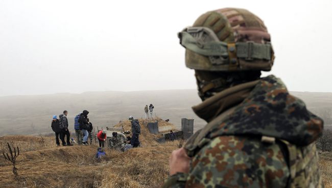 Украинский военнослужащий смотрит на активистов, копающих траншеи на побережье Азовского моря у города Мариуполь. 26 ноября 2018 Украинский военнослужащий смотрит на активистов, копающих траншеи на побережье Азовского моря у города Мариуполь. 26 ноября 2018