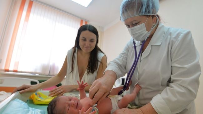 Врач проводит медицинский осмотр новорожденного. Архивное фото Врач проводит медицинский осмотр новорожденного. Архивное фото