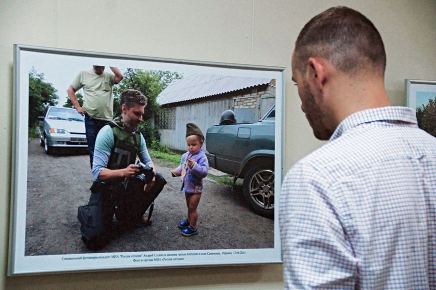 Посетитель у фотографии, на которой изображен фотокорреспондент МИА Россия сегодня Андрей Стенин и мальчик Антон Кобченко в селе Семеновка, на выставке работ фотокорреспондента Андрея Стенина в Луганской галерее искусств