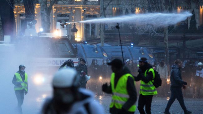 Полиция применяет водометы во время акции протеста желтые жилеты в Париже. 16 декабря 2018 Полиция применяет водометы во время акции протеста желтые жилеты в Париже. 16 декабря 2018