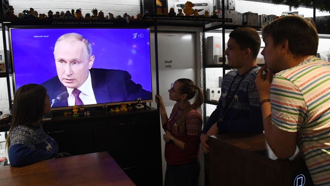 Люди смотрят прямую трансляцию ежегодной большой пресс-конференции президента РФ Владимира Путина в магазине во Владивостоке