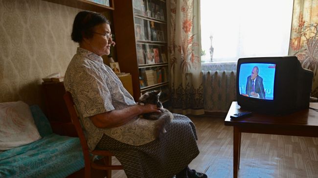 Пенсионерка смотрит прямую трансляцию ежегодной большой пресс-конференции президента РФ Владимира Путина Пенсионерка смотрит прямую трансляцию ежегодной большой пресс-конференции президента РФ Владимира Путина