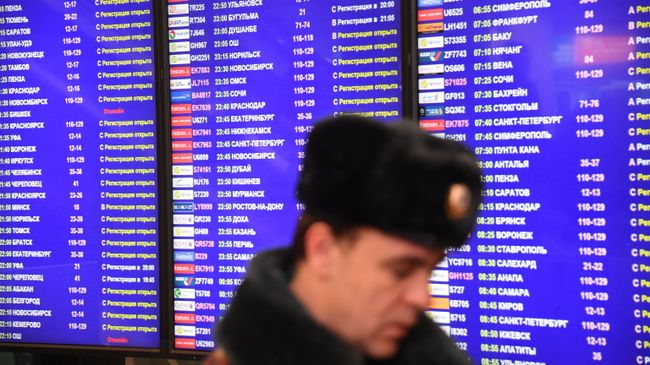Сотрудник полиции у информационного табло в аэропорту Домодедово Сотрудник полиции у информационного табло в аэропорту Домодедово