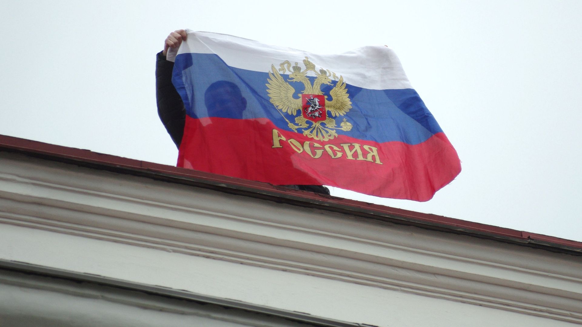 Местный житель с российским флагом на крыше Горсовета в Севастополе - РИА Новости, 1920, 04.05.2025