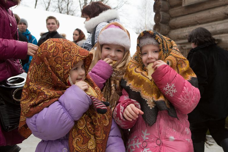 Дети едят блины во время праздничных гуляний на Масленицу Дети едят блины во время праздничных гуляний на Масленицу