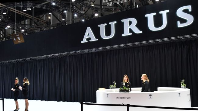 Девушки у информационной стойки стенда Aurus на Женевском автосалоне