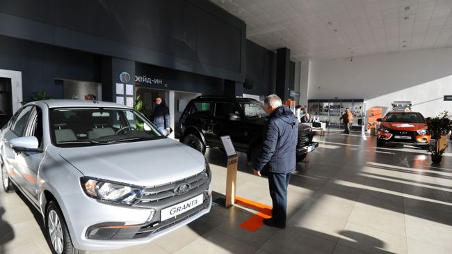 Посетитель рассматривает автомобиль Lada Granta в демонстрационном зале автоцентра Посетитель рассматривает автомобиль Lada Granta в демонстрационном зале автоцентра