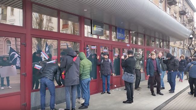 Скриншот видео, на котором националисты облили кровью и обклеили стикерами вход в здание Национального антикоррупционного бюро Украины Скриншот видео, на котором националисты облили кровью и обклеили стикерами вход в здание Национального антикоррупционного бюро Украины