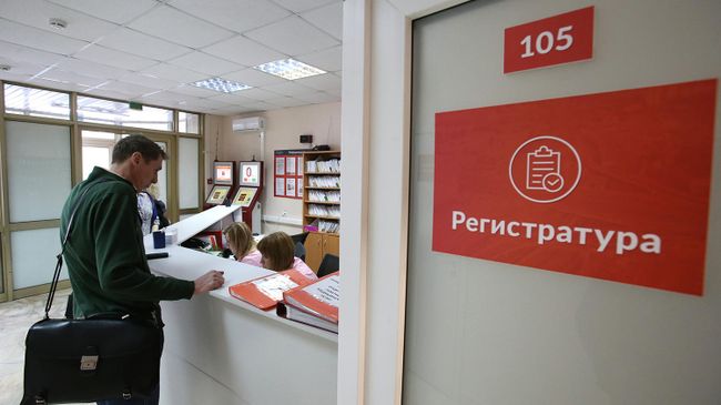 Посетитель у регистрационной стойки в поликлинике Посетитель у регистрационной стойки в поликлинике