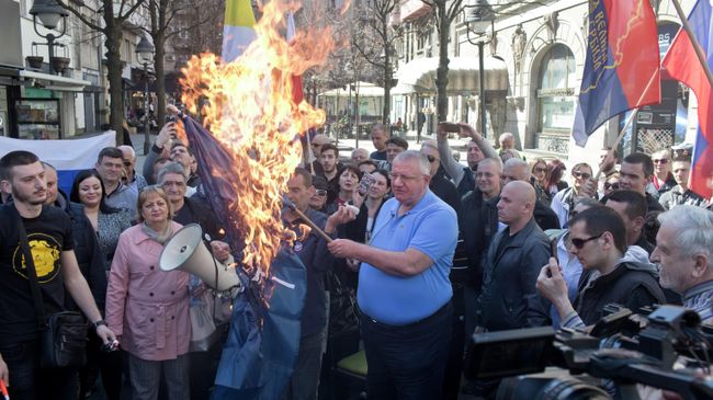 Воислав Сесель, лидер ультранационалистической сербской радикальной партии, держит горящий флаг НАТО на акции протеста в Белграде, Сербия. 24 марта 2019 Воислав Сесель, лидер ультранационалистической сербской радикальной партии, держит горящий флаг НАТО на акции протеста в Белграде, Сербия. 24 марта 2019