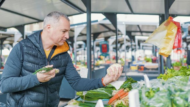 Мужчина выбирает овощи на рынке