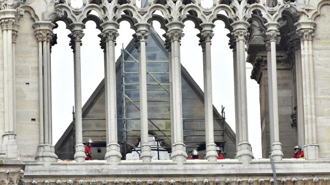 Пожарные осматривают крышу собора Парижской Богоматери после пожара