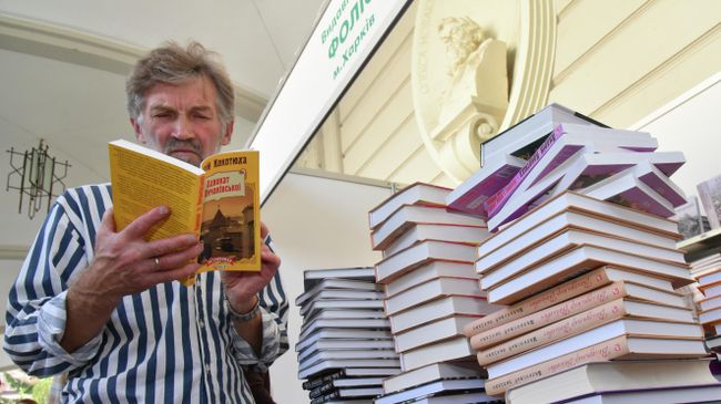 Посетитель читает книгу на книжной ярмарке во Львове Посетитель читает книгу на книжной ярмарке во Львове