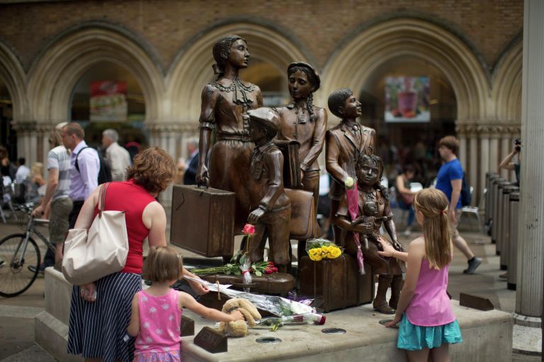 Люди кладут цветы к мемориалу Киндертранспорт, расположенному на станции Ливерпуль-стрит в Лондоне Люди кладут цветы к мемориалу Киндертранспорт, расположенному на станции Ливерпуль-стрит в Лондоне