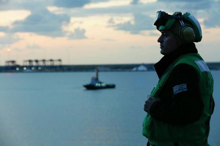 Пилот истребителя смотрит на закат с палубы авианосца ВМС США “Авраама Линкольна, проходящего через Суэцкий канал к берегам Персидкого залива, 9 мая 2019 