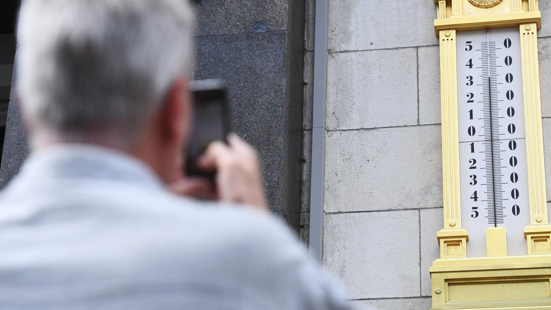 Мужчина фотографирует термометр на здании Государственной Думы РФ в Москве - РИА Новости, 1920, 18.05.2021