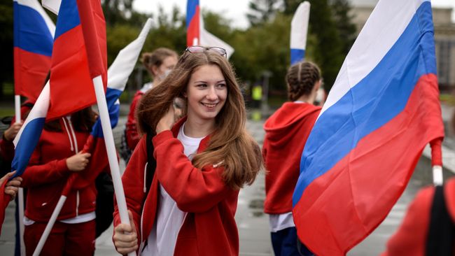 Участники праздничного шествия с флагами России