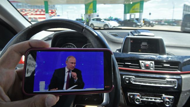 Мужчина смотрит трансляцию прямой линии с президентом России Владимиром Путиным