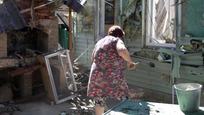 Женщина убирает мусор во дворе жилого дома в Донецке, пострадавшего в результате обстрела Женщина убирает мусор во дворе жилого дома в Донецке, пострадавшего в результате обстрела