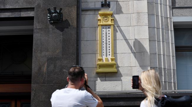 Молодые люди фотографируют термометр на здании Государственной Думы
