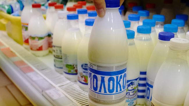 Покупатель держит в руках бутылку молока Покупатель держит в руках бутылку молока