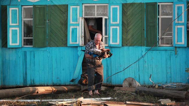 Местный житель возле разрушенного паводком дома в городе Тулун в Иркутской области Местный житель возле разрушенного паводком дома в городе Тулун в Иркутской области