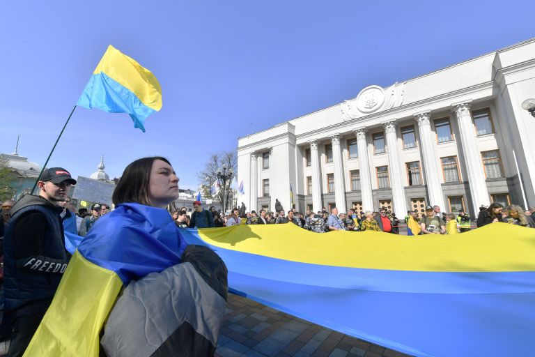 Люди c украинским флагом перед зданием парламента в Киеве Люди c украинским флагом перед зданием парламента в Киеве
