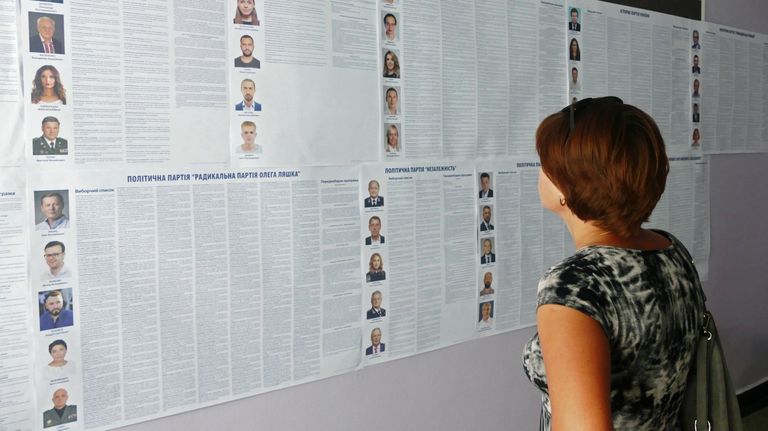 Женщина изучает списки кандидатов на пост депутата в Верховную раду Украины на участке в Черкассах
