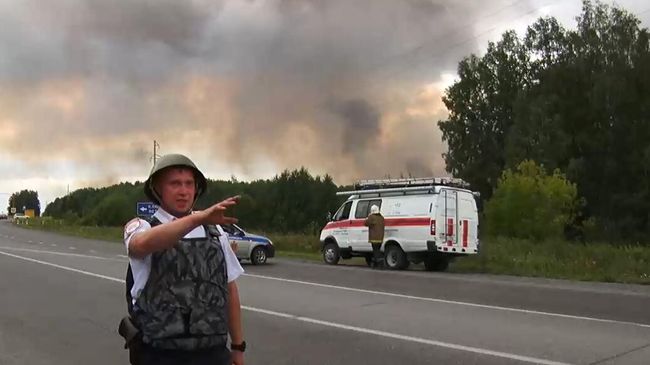 Сотрудник полиции в районе воинской части под Ачинском, где произошли пожар и взрывы на складе хранения артиллерийских боеприпасов. Стоп-кадр с видео