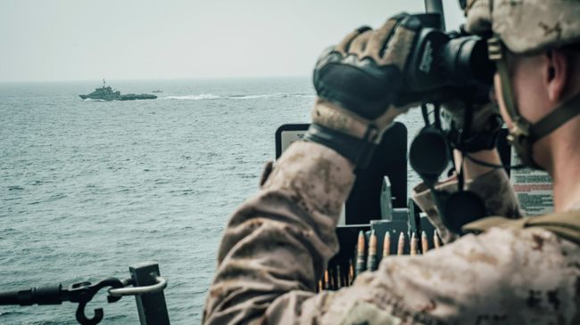Морской пехотинец США наблюдает за иранским кораблем c американского военного корабля USS John P. Murtha во время транзита через Ормузский пролив Морской пехотинец США наблюдает за иранским кораблем c американского военного корабля USS John P. Murtha во время транзита через Ормузский пролив