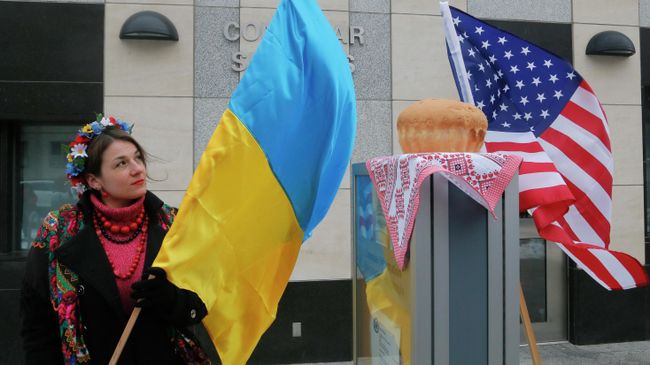 Женщина держит флаг Украины рядом с посольством США в Киеве Женщина держит флаг Украины рядом с посольством США в Киеве