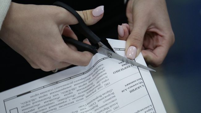 Члены избирательной комиссии проводят процедуру гашения неиспользованных бюллетеней на избирательном участке Члены избирательной комиссии проводят процедуру гашения неиспользованных бюллетеней на избирательном участке