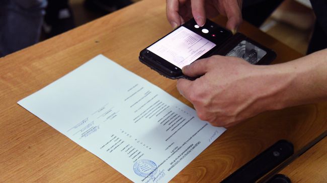 Наблюдатель фотографирует сведения о результатах голосования на избирательном участке Наблюдатель фотографирует сведения о результатах голосования на избирательном участке