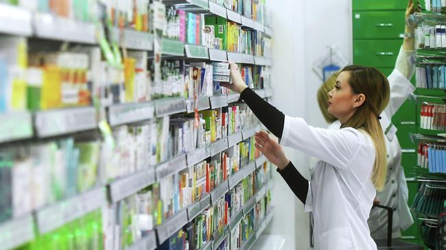 Фармацевт раскладывает лекарственные препараты в аптеке Фармацевт раскладывает лекарственные препараты в аптеке