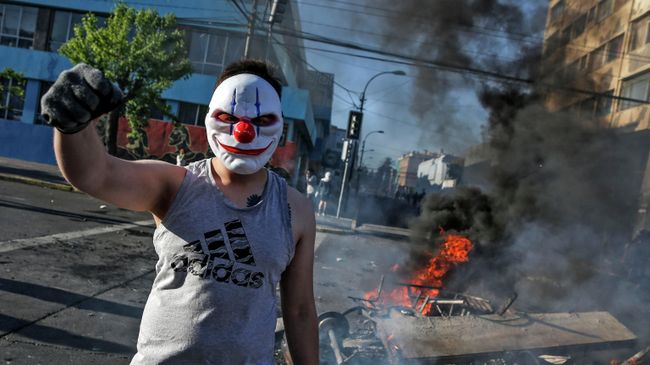 Демонстрант на горящих баррикадах во время акций протеста в Чили Демонстрант на горящих баррикадах во время акций протеста в Чили