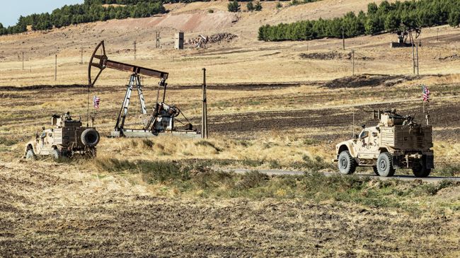 Американские военные автомобили проезжают мимо нефтяной скважины в сирийской провинции Эль-Хасаке Американские военные автомобили проезжают мимо нефтяной скважины в сирийской провинции Эль-Хасаке