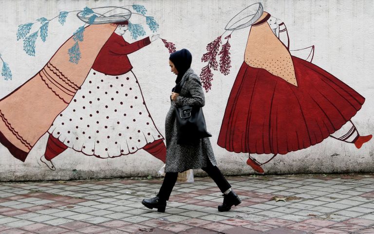 Женщина проходит мимо расписанной стены в Тегеране, Иран 