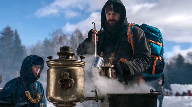 Мужчина наливает горячий чай во время массовых гуляний Мужчина наливает горячий чай во время массовых гуляний