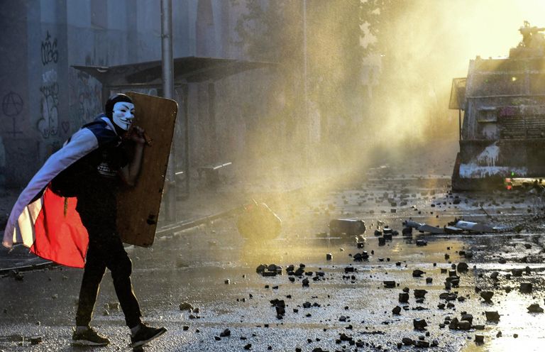 Демонстрант в маске Гая Фокса во время протестов против правительства в Сантьяго Демонстрант в маске Гая Фокса во время протестов против правительства в Сантьяго