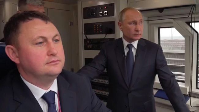 Президент России Владимир Путин в кабине машиниста едет по ж/д мосту через Керченский пролив. Стоп-кадр видео Президент России Владимир Путин в кабине машиниста едет по ж/д мосту через Керченский пролив. Стоп-кадр видео