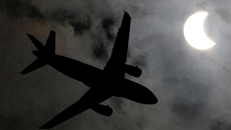 Самолет летит во время солнечного затмения в Бангкоке, Таиланд Самолет летит во время солнечного затмения в Бангкоке, Таиланд