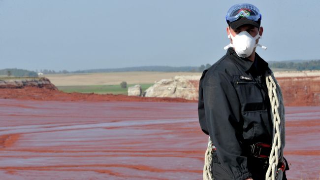 Пожарный в защитной маске возле резервуара с красным шламом в Венгрии Пожарный в защитной маске возле резервуара с красным шламом в Венгрии