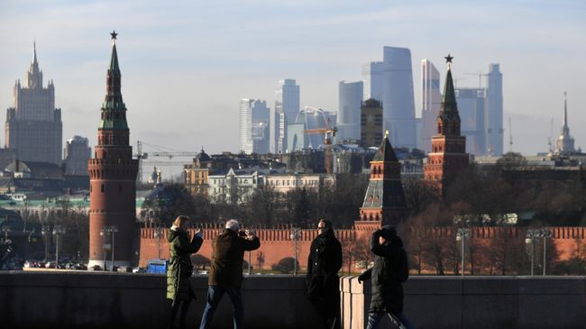 Прохожие фотографируются на Большом Москворецком мосту в Москве
