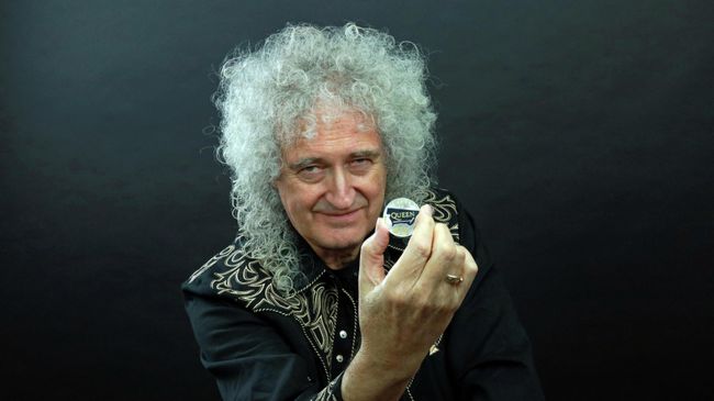 Гитарист группы Queen Брайан Мэй позирует с 5-фунтовой монетой, выпущенной с логотипом группы Гитарист группы Queen Брайан Мэй позирует с 5-фунтовой монетой, выпущенной с логотипом группы