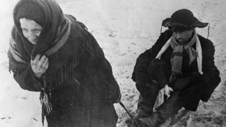 Жители блокадного Ленинграда: женщина везет ослабевшего от голода мужа на санках Жители блокадного Ленинграда: женщина везет ослабевшего от голода мужа на санках