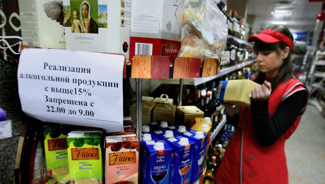 Продавец супермаркета в отделе по продаже алкоголя. Архивное фото Продавец супермаркета в отделе по продаже алкоголя. Архивное фото