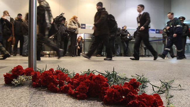 Люди несут живые цветы к месту трагедии в аэропорту Домодедово