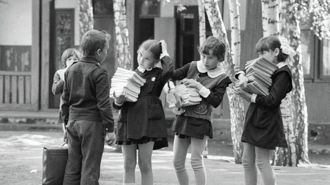 Школьники несут стопки учебников