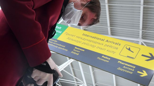 Сотрудник санитарно-карантинного пункта проводит дистанционную термометрию пассажиров, прибывших в аэропорт Сотрудник санитарно-карантинного пункта проводит дистанционную термометрию пассажиров, прибывших в аэропорт